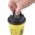 A yellow coffee mug with a black handle lid, featuring a hand gripping the lid.