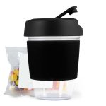 A reusable coffee cup with a black silicone sleeve and a secure lid, accompanied by a pack of colorful jelly beans.