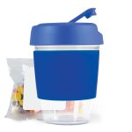 A reusable coffee cup with a blue silicone sleeve and matching lid, accompanied by a package of colorful jelly beans.