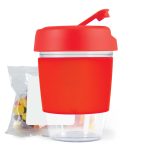 A reusable coffee cup in vibrant red with a lid and a sip spout, accompanied by a small packet of colorful jelly beans.