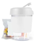 A white reusable coffee cup with a lid, accompanied by a bag of colorful jelly beans.