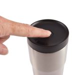 A stainless steel travel mug with a black lid and a finger pressing on the top, featuring a logo.