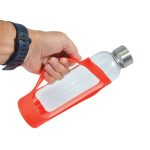 A drink bottle with a clear glass body and a bright red silicone sleeve, held by a hand. It has a metal cap.
