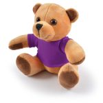A plush teddy bear in brown with a purple shirt, featuring round eyes and soft paws, sitting upright.
