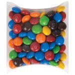 A pillow pack filled with colorful M&M's in various shades, including red, blue, green, yellow, brown, and orange.