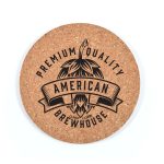A round cork coaster featuring a black design with bold text and a logo, showcasing a rustic, natural look.