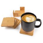 A black mug on a bamboo coaster, surrounded by a set of five additional bamboo coasters.