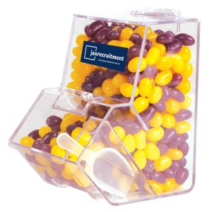 A clear dispenser filled with purple and yellow jelly beans, featuring a logo on the front.