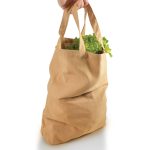 A short handle shopper bag made of natural-colored fabric, filled with fresh green lettuce.