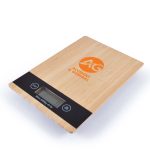 A wooden kitchen scale with a digital display and the logo "AG Accident & General" prominently featured on the surface.