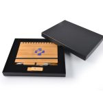 A bamboo notebook with a pen and wooden USB drive, presented in a black gift box. The notebook features a branding logo.