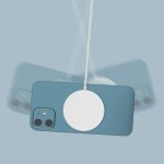 A white magnetic wireless charger is attached to a blue phone on a light blue background.