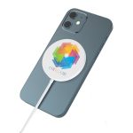 A magnetic wireless charger in a circular design with a colourful logo, placed on a smartphone. The charger is white.