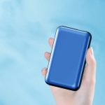 A blue power bank held in a hand, designed for charging devices, featuring a sleek surface and branding.