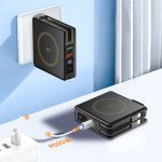 A black magnetic travel charger sits against a wall, showing USB ports and charging cables plugged in.