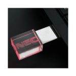 A transparent pink 3D crystal flash drive is inserted into a laptop USB port. The device has a logo.