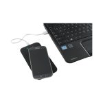 A black wireless charger with a smartphone on top, placed next to a laptop keyboard.