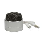 A compact silver Bluetooth speaker with a mesh grille and attached charging cables.