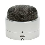 A compact silver Bluetooth speaker with a black mesh top and a USB charging port at the base.