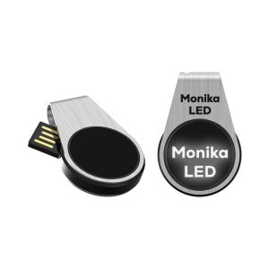 A silver LED flash drive with a black circular section and a branding logo. The drive has a retractable connector.