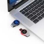 A red and black Monika LED flash drive is plugged into a laptop, showcasing its sleek design and branding.