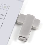 A silver Executive Twist Flash Drive is plugged into a laptop, positioned beside the keyboard.