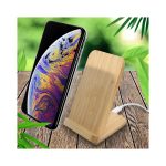 A wooden bamboo wireless charger stands upright beside a smartphone, set against a leafy background.