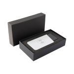 A grey and white wireless power bank in a black box with foam padding. It has a logo on the surface.