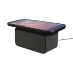 A black wireless charging speaker with a phone placed on top, featuring a mesh speaker grille and a charging cable.
