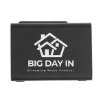 A black wireless charger with speaker features a house logo and promotional text for a music festival.