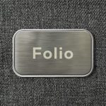 A metallic rectangular tag with the word "Folio" engraved on a textured grey background.