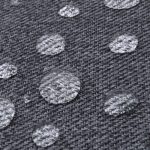 A close-up of grey fabric with water droplets beading on its surface, showcasing its water-resistant texture.