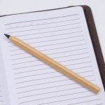 A bamboo pen resting on a lined notebook page, featuring a simple and natural design.
