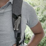 A grey multi-tool attached to a grey shoulder strap, featuring various tools and a slim design.