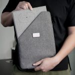 A person holding a grey Evopad Charge Eco Mouse Pad, featuring a textured fabric surface and a logo on the front.