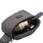 A grey anti-theft sling bag with a drink bottle, sunglasses, and a wallet visible inside.