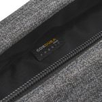 A close-up of a grey fabric bag showing a hidden zip and tag, featuring a logo on the inner lining.