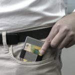 A silver RFID wallet is partially placed in a pocket, featuring a dark strap.