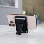 A phone with a black wallet case and kickstand, resting on a marble surface, featuring visible credit cards.