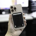 A smartphone with a black cardholder attachment, featuring a sleek design and a neutral-coloured case.