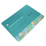 A turquoise wireless charger and mouse pad with a colorful geometric design along one edge and a logo.