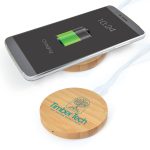 A bamboo wireless charger in a circular shape with a logo, next to a smartphone displaying a charging battery icon.