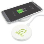 A round white wireless charger with a logo, beside a smartphone displaying a charging battery icon.