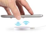A wireless charger with a white circular base and a smartphone hovering above it, indicating charging.