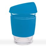 A reusable coffee cup in a clear glass design features a bright blue silicone lid and sleeve.