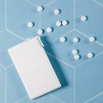 A rectangular white container with scattered white mints on a geometric blue background.