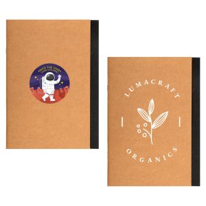 A brown A5 notebook with a space-themed sticker on one side and a logo on the other. Features a black spine.