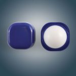 A Cube Lip Balm with a rounded, smooth white balm inside a square navy blue container, featuring a twist-off lid.