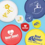 A collection of colorful promotional frisbees in white, blue, red, and yellow, featuring various logos and designs.