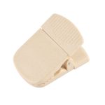 A beige magnetic clip with a textured grip, designed for holding notes or papers, featuring a branding logo.